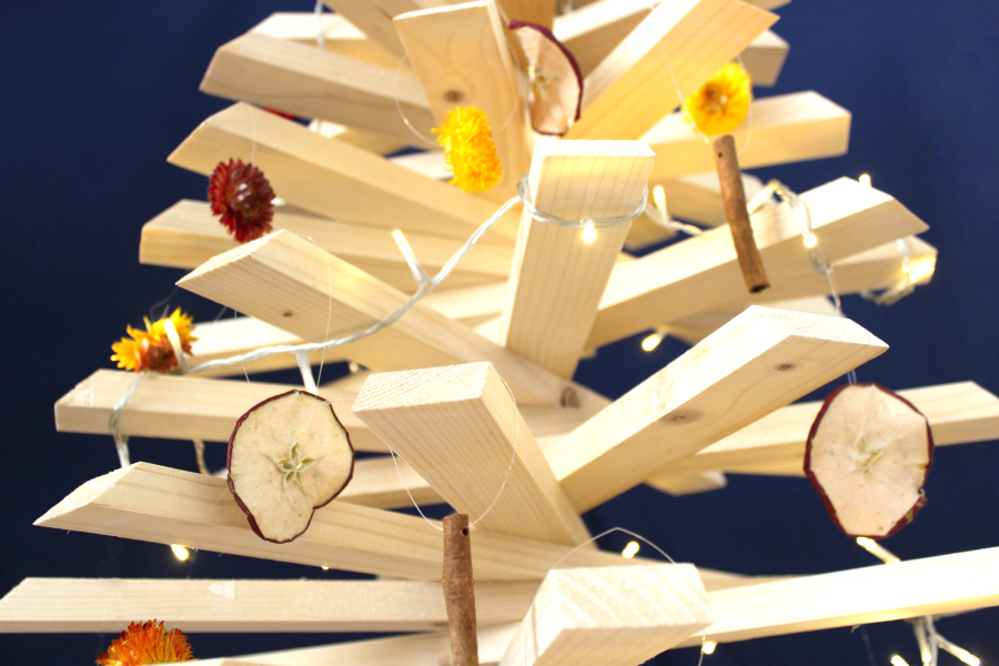 Sapin de Noël en bois recyclé décoré de suspensions naturelles: fleurs d'immortelle, pomme et cannelle.